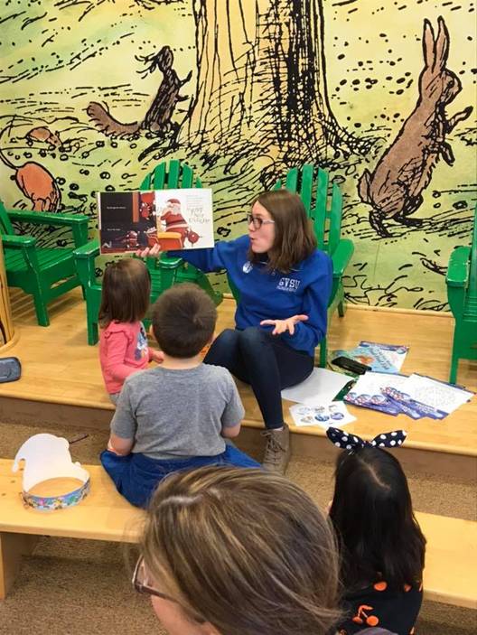 Ellie reading a picture book to young students